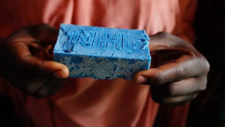 A girl holds a soap bar with the inscription NHF