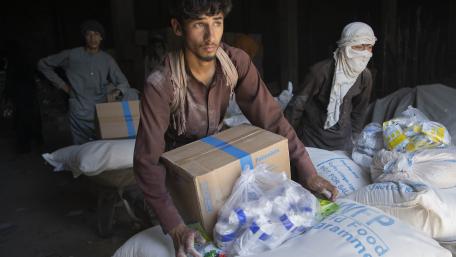 A group of young men carry boxes and bags with food