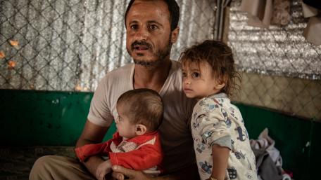 A father with his two children, inside a tent