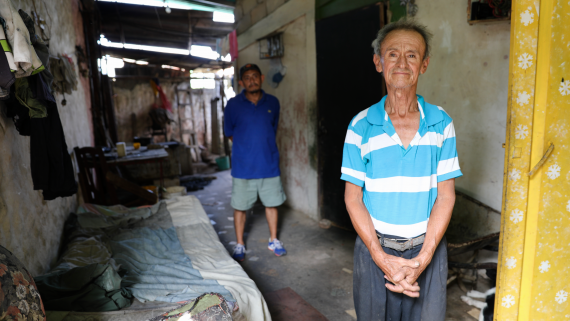 An older man standing, with his son on the back