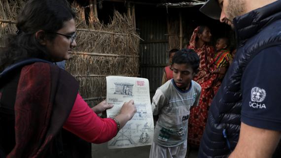 A woman shows a poster to a humanitarian worker