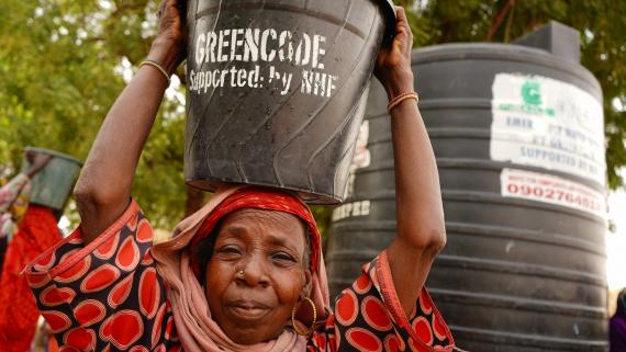 A woman holds a bucket of water over her head