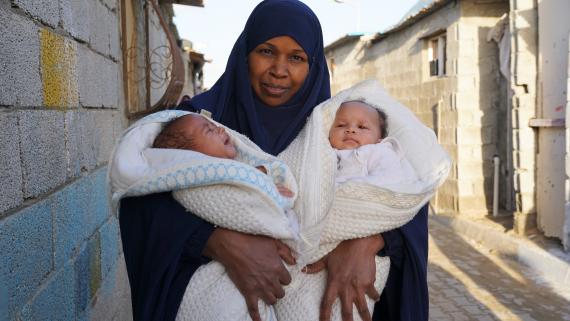 A mother holds her two babies in her arms