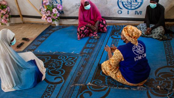 A humanitarian worker talks to three woman inside a tent