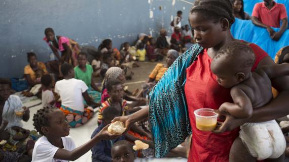 A woman hands a piece of bread to her son