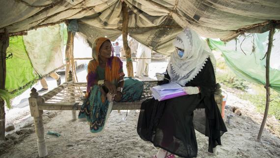 A humanitarian worker talks with a woman inside a tent