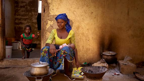 A displaced mother with her baby and daughter prepares some food at the camp for people who fled Mondoro, in Gao.