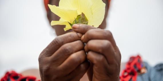 A woman covers her face behind a flower