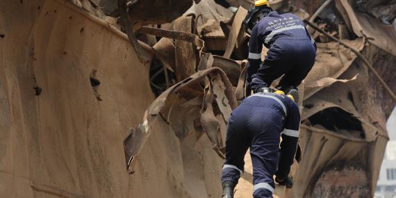 Two men climbing a destroyed boat during a urban rescue mission