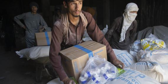 A group of young men carry boxes and bags with food