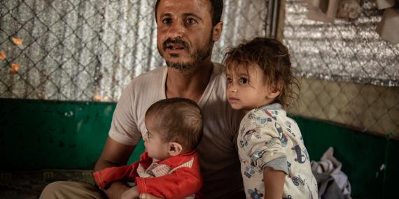 A father with his two children, inside a tent