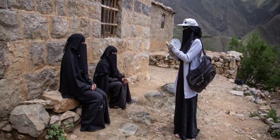 A community health worker visits a family to conduct a physically distant information session